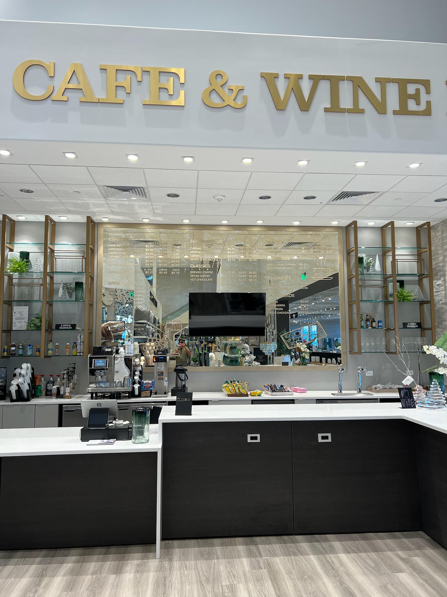 Bar area with custom architectural millwork, gold metallic shelving and signage, and dark wood laminate cabinetry.