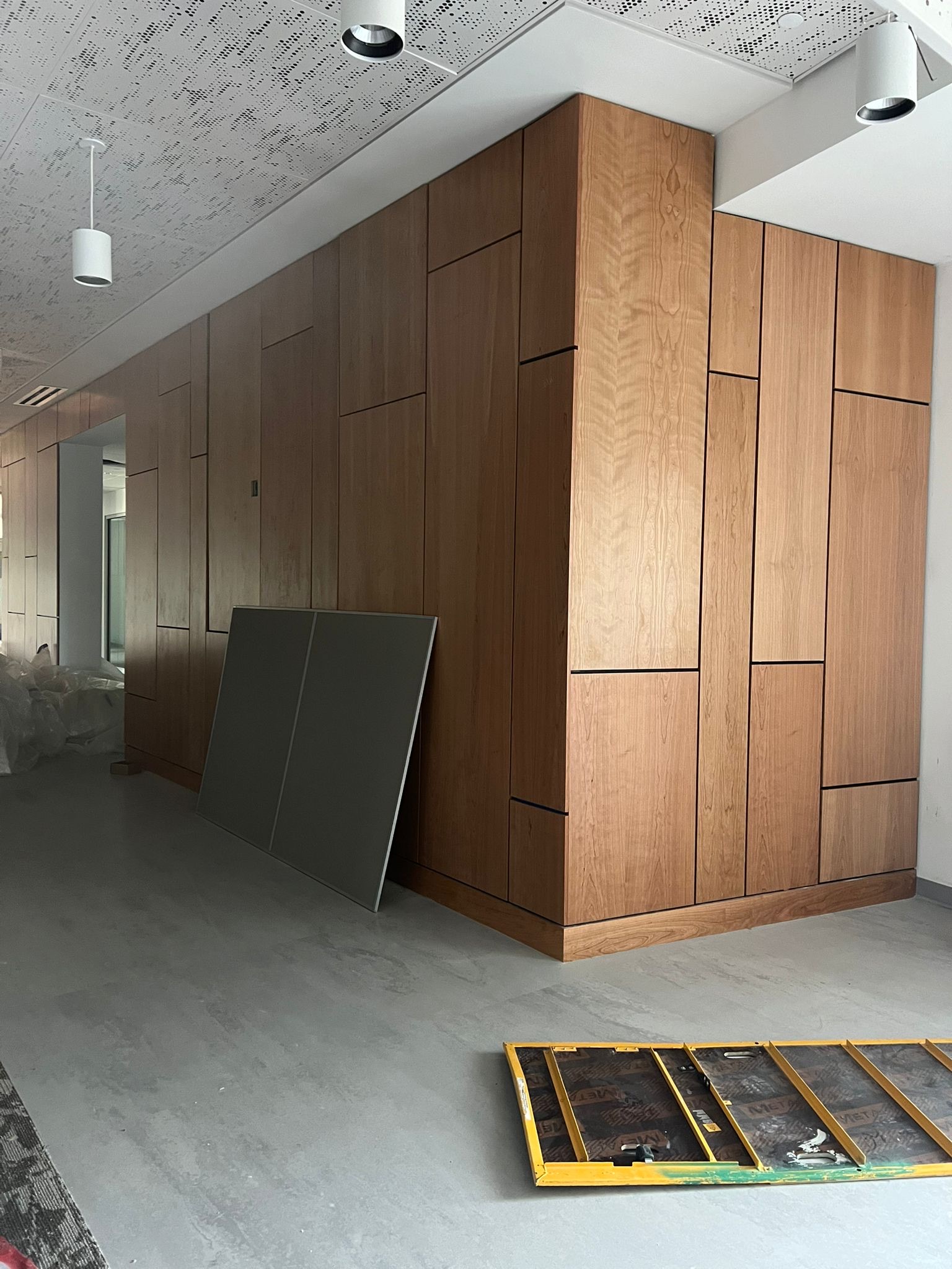 Natural cherry wood paneling with integrated doors and contrasting black reveals in a commercial space.