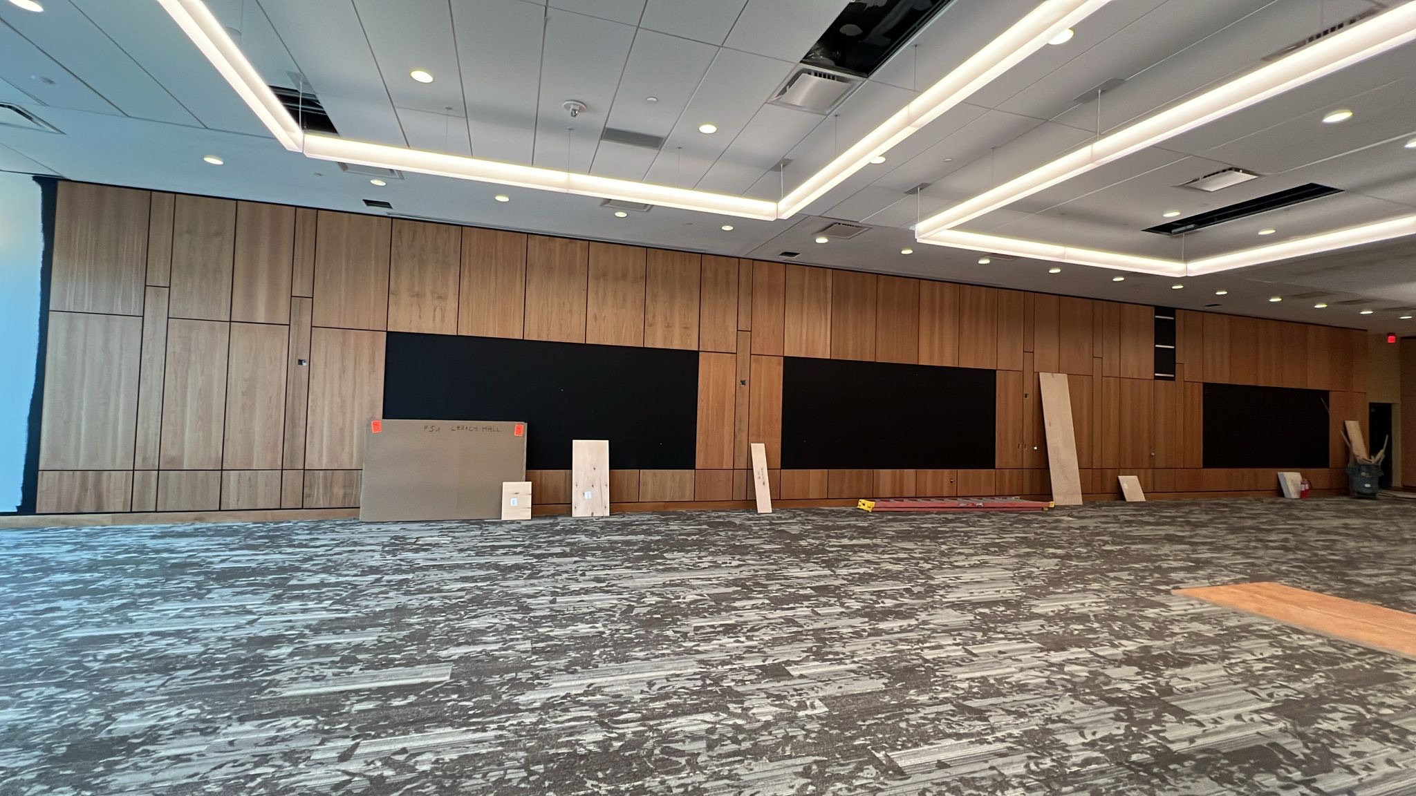 Conference room with architectural millwork paneling in warm wood finish and integrated display areas awaiting installation