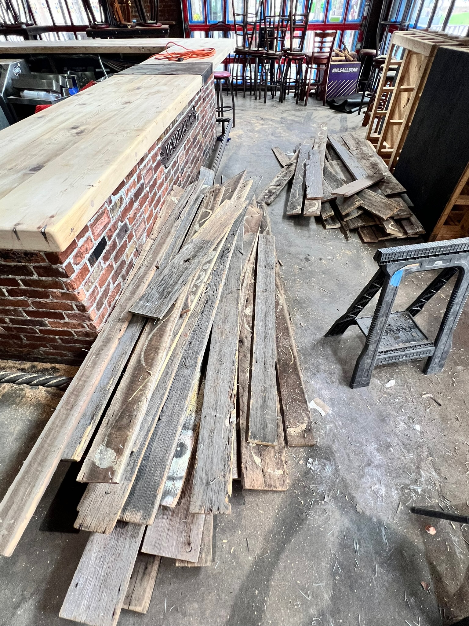 Reclaimed wood planks and a partially constructed bar with a brick base and light wood countertop in a commercial setting.