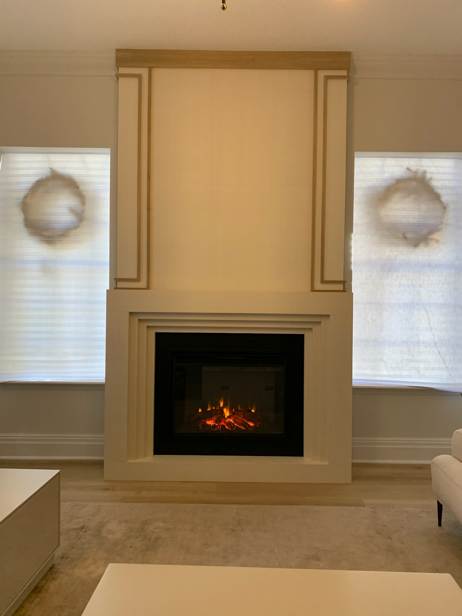 Living room with built-in fireplace featuring a white surround and light wood trim, flanked by windows.