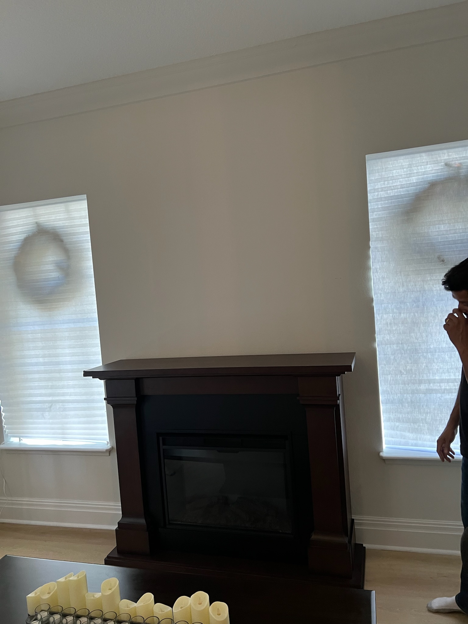 Formal living room with an electric fireplace featuring a dark wood mantel and crown molding. Two windows with horizontal blinds flank the fireplace.