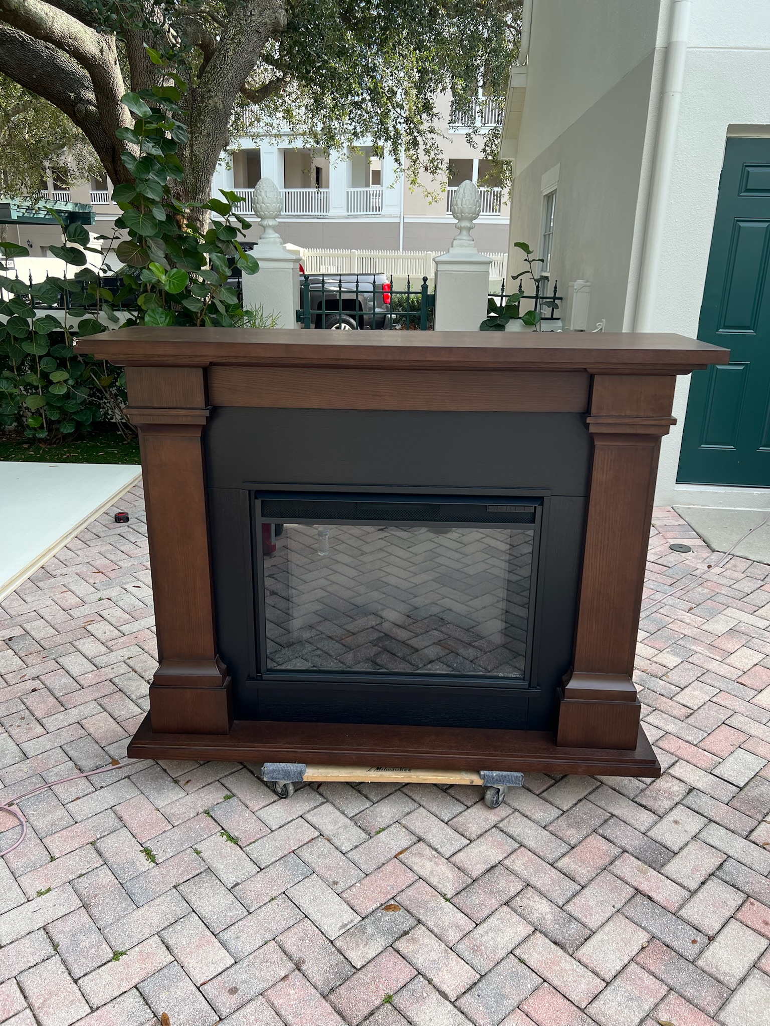 Stained mahogany fireplace millwork with fluted pilasters and substantial mantel molding, featuring an electric firebox.