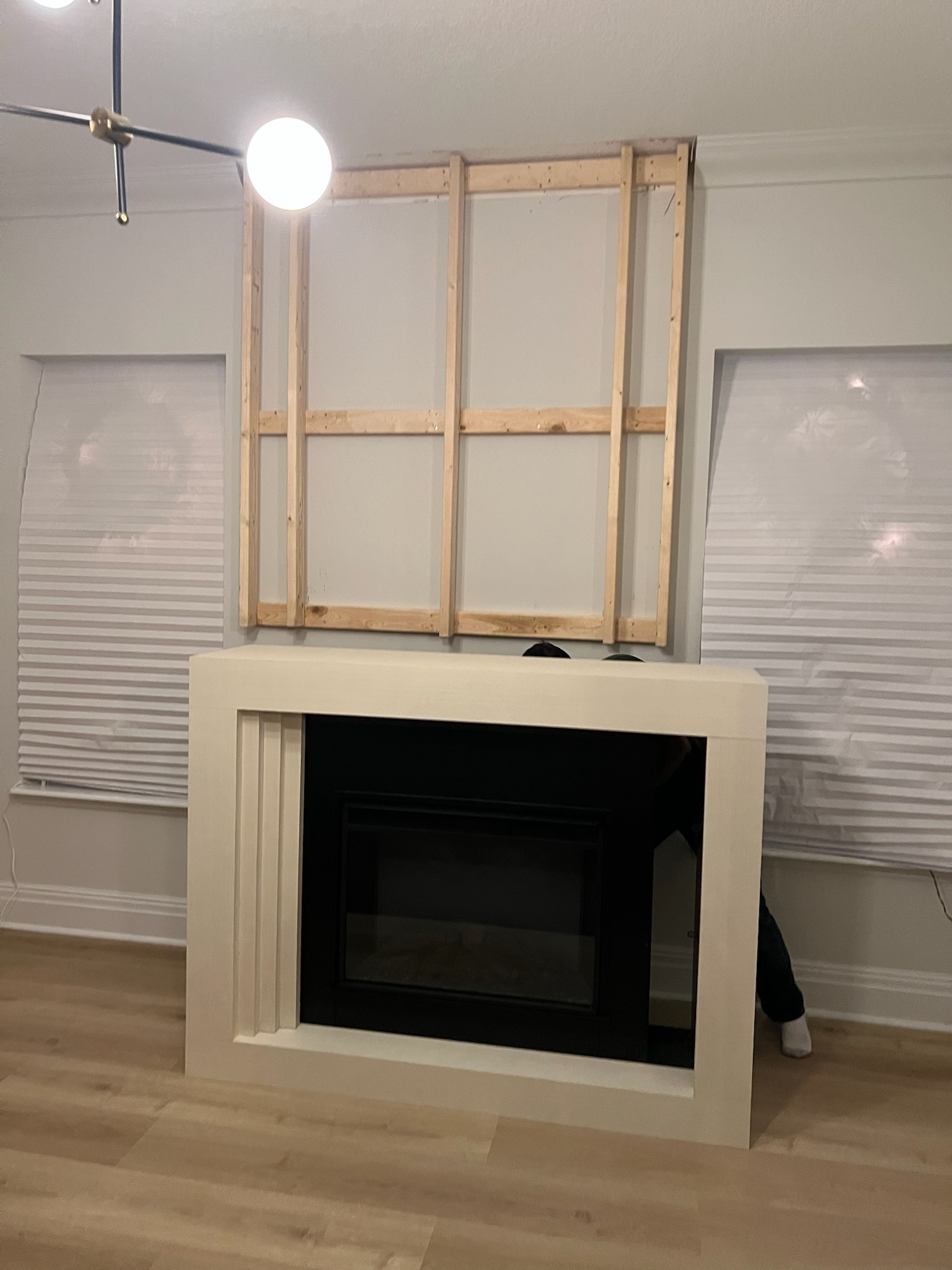 Unfinished living room fireplace millwork in painted wood and a custom wood frame for a TV enclosure.